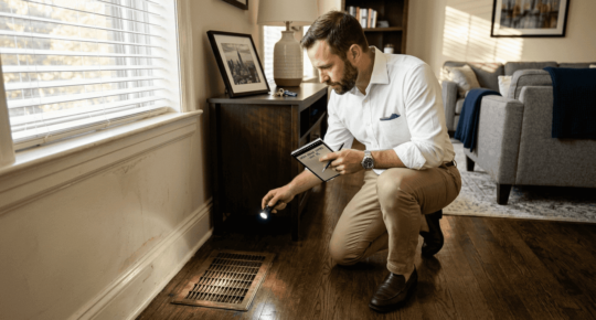 Agent inspecting air vent in apartment