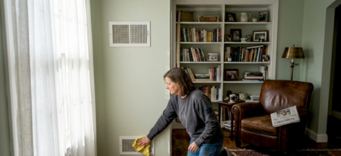 Seller cleaning wall vent in home