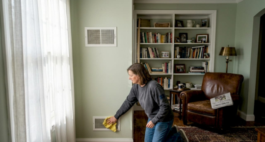 Seller cleaning wall vent in home