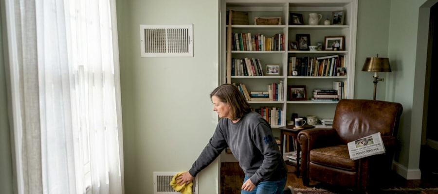 Seller cleaning wall vent in home