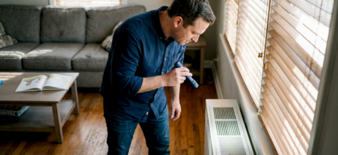 Homeowner inspecting living room HVAC vent