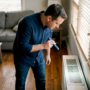 Homeowner inspecting living room HVAC vent
