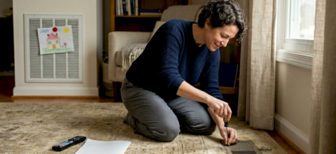 Homeowner checking air duct vent in living room