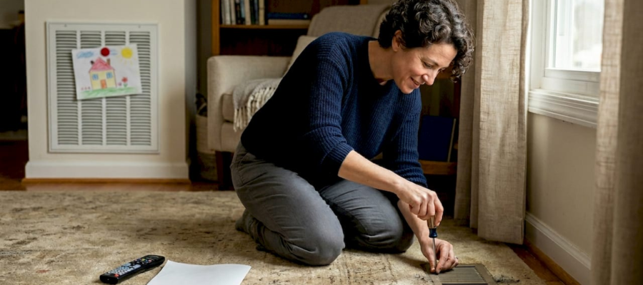 Homeowner checking air duct vent in living room