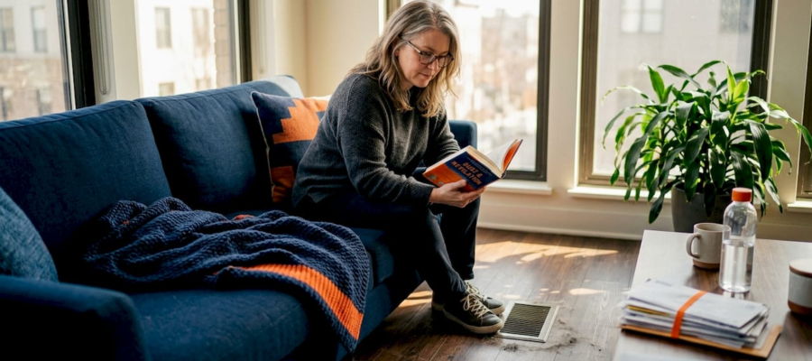 Woman relaxing near sunlit floor vent