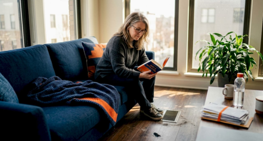 Woman relaxing near sunlit floor vent