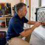 Homeowner replacing HVAC air filter in basement