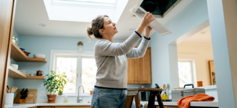 Woman inspecting home air vent register
