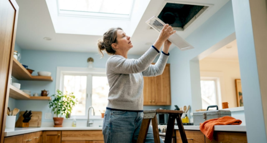 Woman inspecting home air vent register