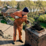 Chimney sweep inspecting chimney on roof