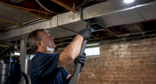 Technician inspecting residential ductwork in attic