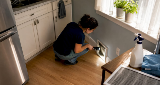 Tenant inspecting living room air duct