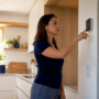 Woman adjusting thermostat settings indoors