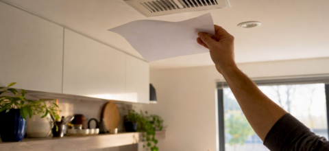 Hand holding paper fluttering at air vent