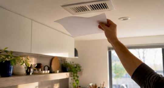 Hand holding paper fluttering at air vent