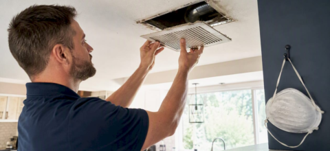 Hands removing home ceiling air vent register