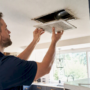 Hands removing home ceiling air vent register