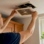 Tenant removing bathroom fan cover for inspection