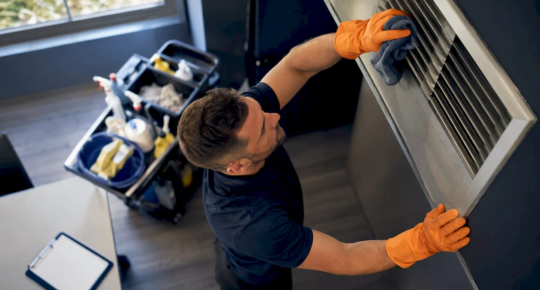 Hands wiping HVAC duct register cover