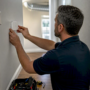 Technician installing air quality sensor indoors