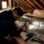 Technician inspecting air ducts in home basement