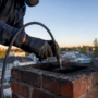 Hands cleaning chimney flue with rotary brush