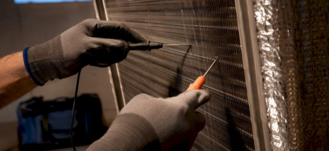 Technician measuring temperature across HVAC coil