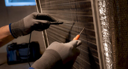 Technician measuring temperature across HVAC coil