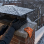 Technician inspecting chimney cap on snowy roof