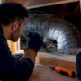 Technician inspecting animal remains inside ductwork
