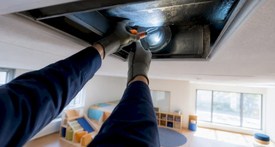 Technician inspecting daycare classroom air duct