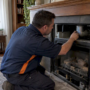 Technician inspecting residential gas fireplace vent