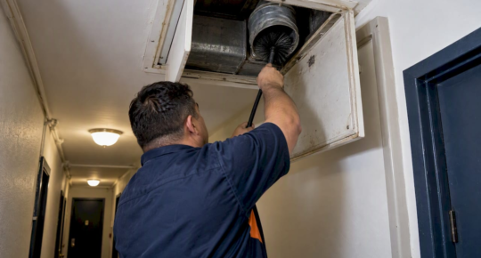 Technician cleaning an apartment dryer exhaust duct