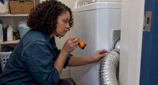 Property manager inspecting a dryer vent connection