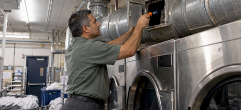 Technician inspecting a hotel dryer exhaust duct