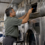 Technician inspecting a hotel dryer exhaust duct