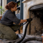 Chimney sweep cleaning a brownstone fireplace